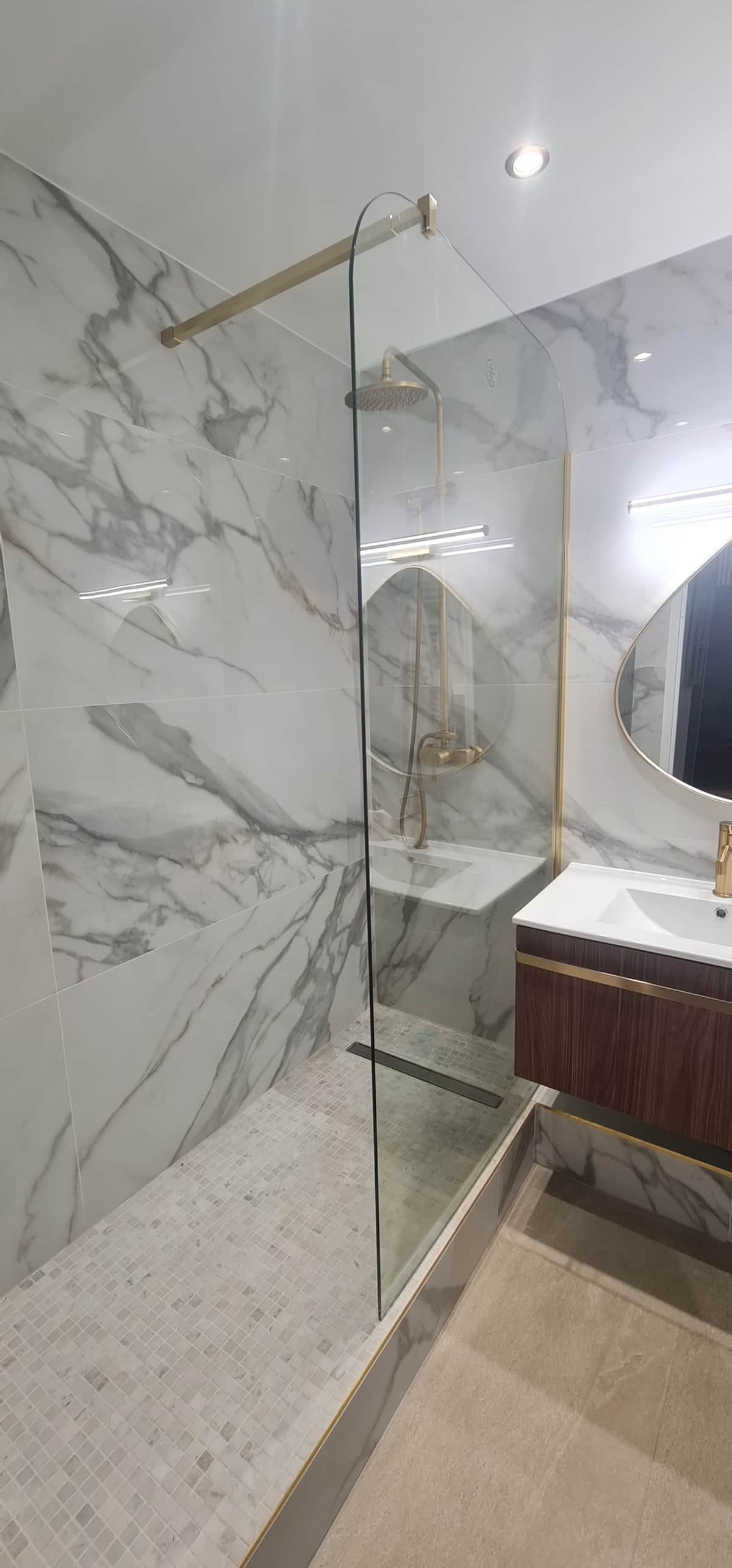 Salle d'eau en marbre avec douche italienne et robinetterie dorée